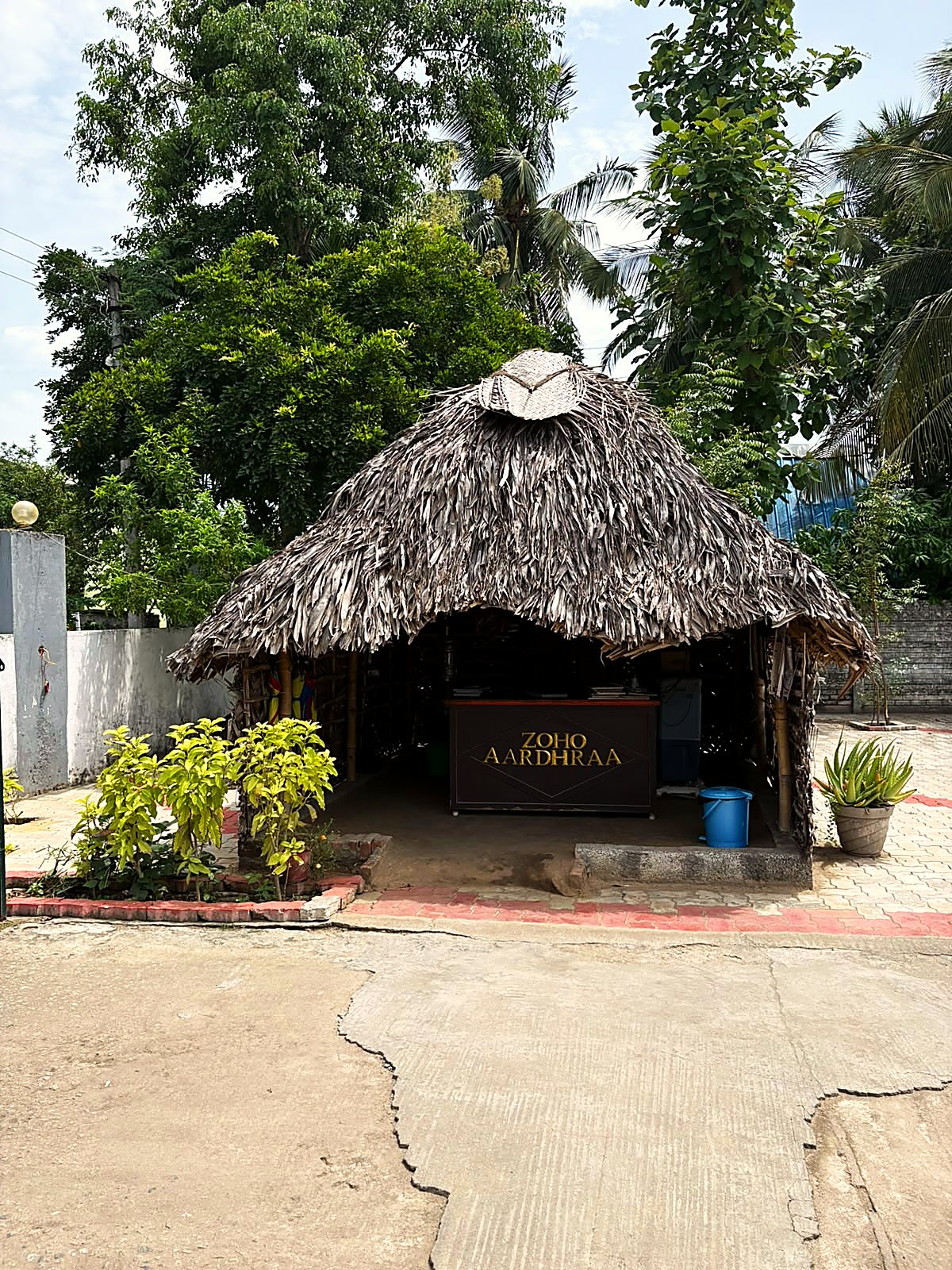 A palm-thatched hut at the entrance to the Kurichi office, with a reception desk inside carrying the words Zoho Aardhraa.